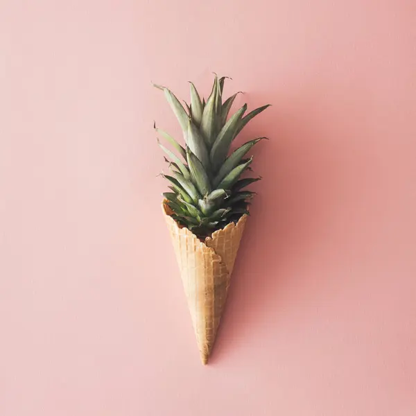 Pastel pembe arka planda ananas yapraklı dondurma külahı. Meyve ve ve şeker kavramı..