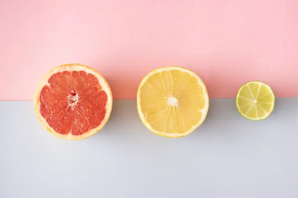 Açık pembe ve gri arka planda greyfurt ve limon dilimi. Minimum düz katman. Yaratıcı kavram.