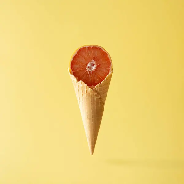 Sarı arka planda dondurma külahlı greyfurt. Yemek yaratıcı kavram.