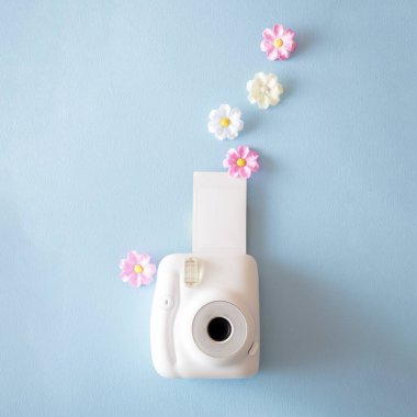Polaroid kameralı yaratıcı bir kavram ve açık mavi arka planda fotokopi alanı olan çiçekler.