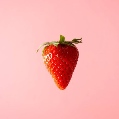 Pastel pembe arka planda yüzen çilek. Yaratıcı gıda konsepti.