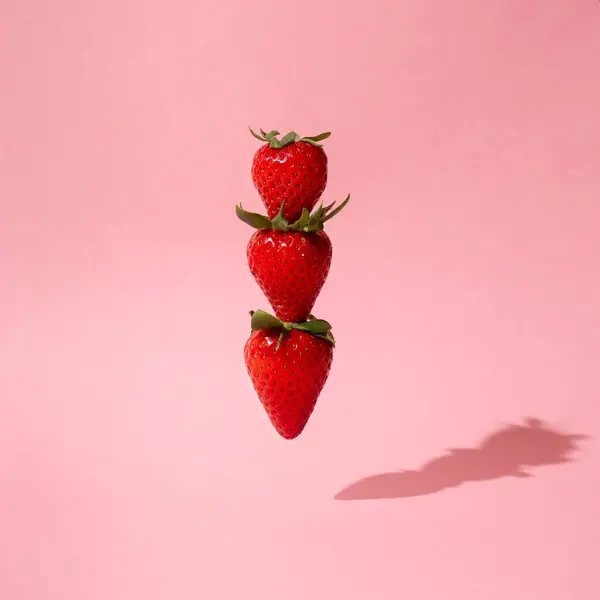 Pembe arka planda yüzen ağaç çilekleri ile yaratıcı yaz meyvesi kavramı