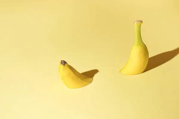 Açık sarı arka planda iki muz parçasıyla yaratılmış yaratıcı bir kavram. Minimum.