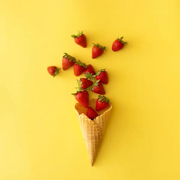 Sarı arka planda çilekli dondurma külahı. Yaratıcı gıda kavramı.