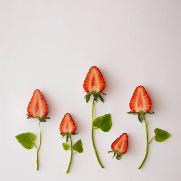 Beyaz bir sırt üzerinde çilek ve yeşil yapraklarla yapılmış renkli parlak çiçekler.