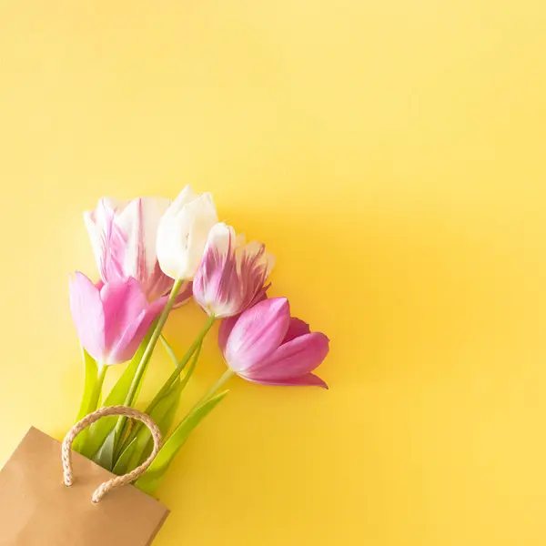 Parlak sarı bir sırt çantasındaki renkli laleler. Düz kat. Boşluğu kopyala.