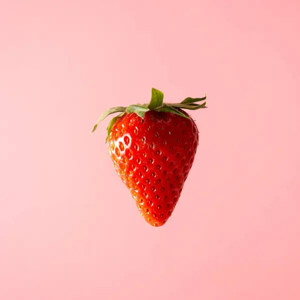 Pastel pembe arka planda yüzen çilek. Yaratıcı gıda konsepti.