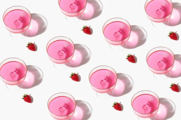 Beyaz bir arka planda şampanya, pembe cam ve çilekten yapılmış yaratıcı parti deseni.