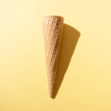 Sarı arka planda gölgesi olan güneşli dondurma külahı. Minimum yaz kavramı.