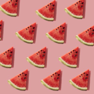 Pastel pembe arka planda karpuz dilimleriyle oluşturulmuş yaratıcı bir bileşim.