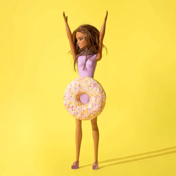 Kız bebek ve donutların sarı arka planda yaratıcılığı. Boşluğu kopyala