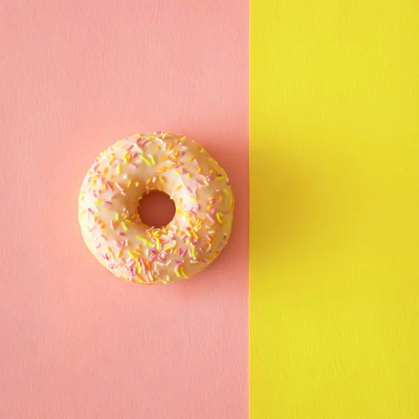 Açık pembe jöleli donut ve sarı ve pembe geri sarılı şekerler. Düz katlı. Boşluğu kopyala.