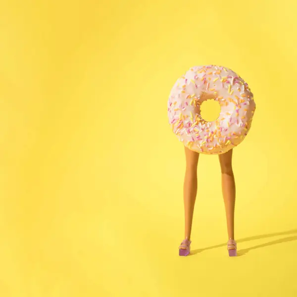 Yaratıcı gıda kavramı, donutlar ve mor sandaletli bebek bacakları ile sarı arka plan. Boşluğu kopyala.