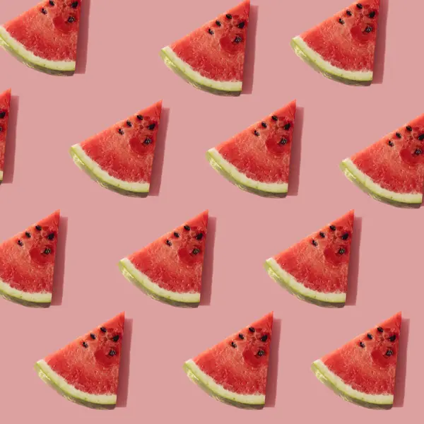Pastel pembe arka planda karpuz dilimleriyle oluşturulmuş yaratıcı bir bileşim.