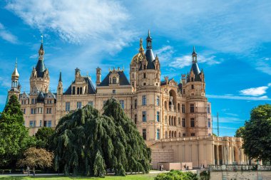 Geniş, mavi bir gökyüzünün altında, verimli yeşilliklerle çevrili, karmaşık mimari detaylar içeren tarihi bir dönüm noktası bulunuyor..