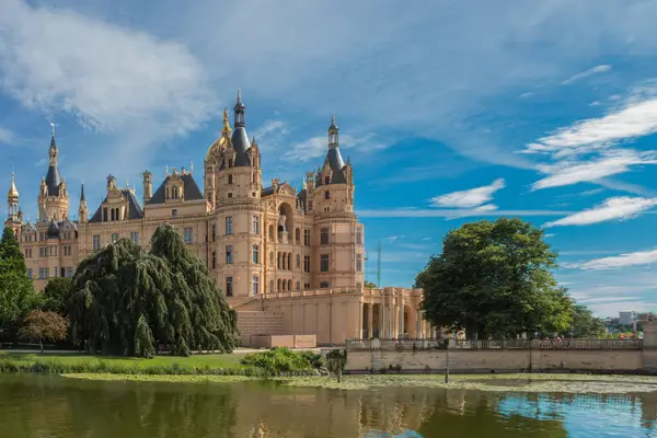 Sakin suların yanında büyük bir mimari mucize yükseliyor, parlak bir gökyüzü altında karmaşık tasarımlar sergiliyor, bereketli yeşilliklerle çevrili sakin gölü yansıtıyor..