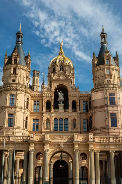 Yüksek kuleleri ve altın aksanı olan görkemli bir yapı mavi gökyüzünün arka planına doğru yükseliyor, mimari ihtişamı somutlaştırıyor..