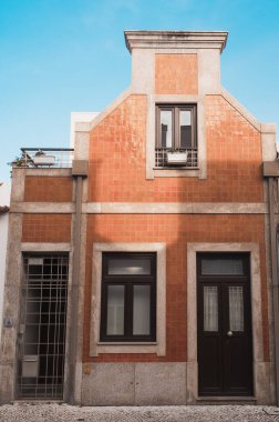 Sessiz bir yerleşim bölgesinde portakal seramik fayanslar ve granit çerçeveli bir Portekiz evi cephesi.