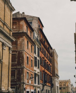 Bir sıra eski İtalyan binaları, taşra cazibesi, sıcak renkler, kepenkli pencereler ve klasik Roma sokak atmosferi sergileniyor..