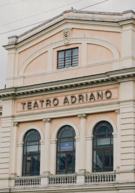 Roma 'daki Teatro Adriano cephesi neoklasik tasarım, pastel tonlar ve dekoratif elementlerle.