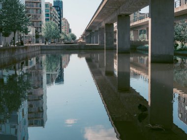 Kopenhag 'ın modern kentsel alanındaki sakin kanal suyuna beton köprü ve şehir binaları yansıdı.