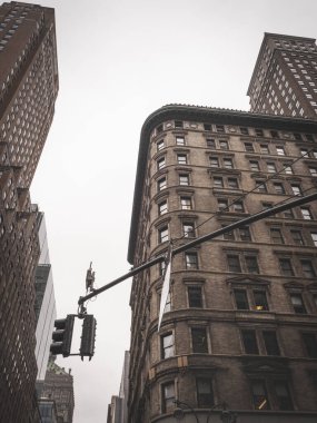 New York 'un mimari karışımında klasik üçgen köşeli bina. Tarihsel tuğla cephesi, kıvrımlı köşe ve yüksek gökdelenler klasik bir şehir atmosferi yaratıyor. Trafik ışıkları bulutlu gökyüzünün altındaki kentsel kompozisyonu çerçeveliyor..