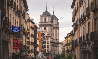 Madrid, İspanya 'da sokak manzarası, tarihi mimari, geleneksel cepheler ve kasvetli bir gökyüzünün altında Baslica de San Francisco el Grande' nin ikiz kuleleri sergilenmektedir. Kültürel derinliğe sahip şehir cazibesi.