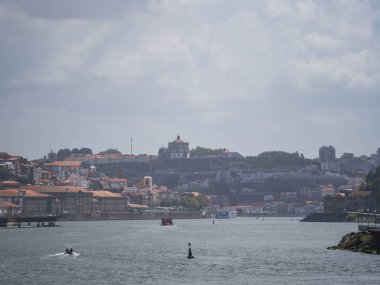 Vila Nova de Gaia ve Porto 'nun dramatik bulutlu bir gökyüzü altında Douro Nehri boyunca gökyüzü manzarası. Tarihsel nehir kenarı manzarası gelenek ve modernliği harmanlıyor.