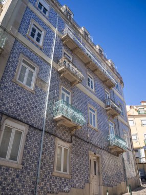 Gökyüzünün altında klasik mavi azulejolar olan güzel döşenmiş Lizbon binası. Balkonlar ve demir işçiliği Portekizlilerin eşsiz fayans mirası ve mimari zarafetini ön plana çıkarıyor.