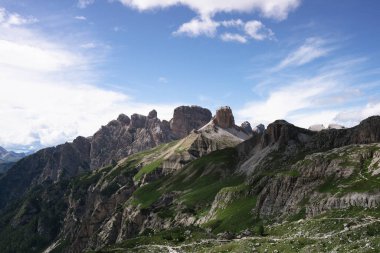 İtalya 'daki Dolomites dağlarının panoramik manzarası. Parlak mavi bir yaz gökyüzünün altında yeşil dağlık yamaçların üzerinde yükselen dramatik kayalık tepeler.. 