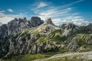 İtalya 'nın Dolomitler şehrinde bulutlu, dramatik bir gökyüzünün altında katmanlı kayalık sırtları olan görkemli bir dağ sırasının panoramik görüntüsü..