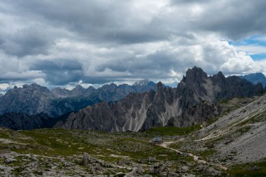 Aşağıdaki vadide ıssız bir dağ kulübesi olan kasvetli bulutlu bir gökyüzü altında yakalanan Dolomitlerin şaşırtıcı engebeli tepeleri..