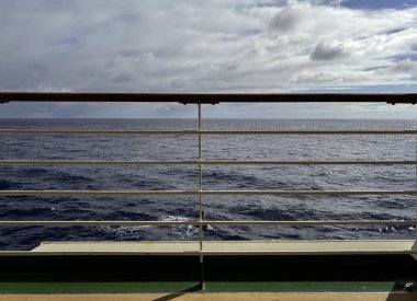 Bir yolcu gemisinin güvertesindeki korkulukların arasından sakin bir deniz manzarası