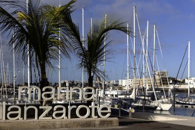 ARKIŞ, LANZAROTE, CANAROTE ADALARI - 13 Şubat 2025: Lanzarote Marina için arka planda botlu büyük işaret