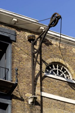 LONDON, İngiltere - 26 Mart 2025: Batı Hindistan Quay 'deki Viktorya dönemi tuğla depolama binasında klasik bir sanayi makarası