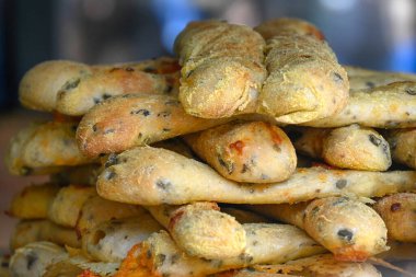 Bir gıda pazarındaki fırında taze peynirli ve zeytinli ekmek çubuklarının yakın çekimi.