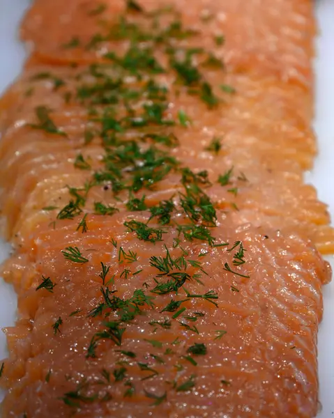 Yiyecek pazarındaki balıkçıların tezgahının tepesine maydanoz serpiştirilmiş somon (Gravlax) yakın plan.