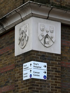 LONDON, İngiltere - 17 Mayıs 2025: St Thomas Yolu 'ndaki hastanenin taş oymalı Arma Arması ile Erkekler Hastanesi Kanser Merkezi' ni imzalayın
