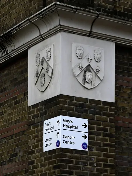 LONDON, İngiltere - 17 Mayıs 2025: St Thomas Yolu 'ndaki hastanenin taş oymalı Arma Arması ile Erkekler Hastanesi Kanser Merkezi' ni imzalayın