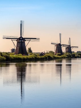 NETHERLANDS - 07 / 04 / 2019: Zaanse Schans 'taki tarihi yel değirmenleri sabahın erken saatlerinde bir kanala yansıyarak