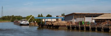 KRIMPENERWAARD, NETHERLANDS - 4 Temmuz 2019: Niewe Maas Nehri üzerindeki panorama bölgesi ve yük gemisi manzarası