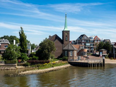 KRIMPEN AAN DE LEK, NETHERLANDS - 4 Temmuz 2019: Lek Nehri ve Kerkaandelek Kilisesi üzerindeki feribot istasyonunun görüntüsü