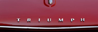 LONDON, İngiltere - 31 Mayıs 2025: Kırmızı Triumph Herald Convertible klasik araba krom adı panoraması