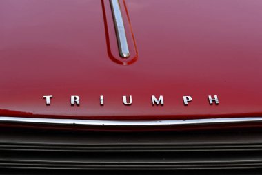 LONDON, İngiltere - 31 Mayıs 2025: Kırmızı Triumph Herald Convertible klasik arabanın krom adı