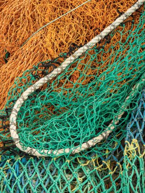 Green and orange fishing nets on a quayside