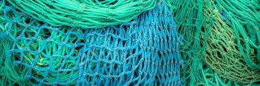 Panorama of pile of colourful fishing nets on a quayside for use as a background texture