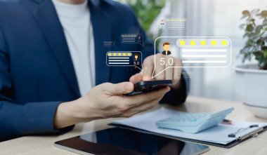Asyalı müşterinin akıllı telefondan 5 yıldız aldığı yakın çekim. El tıklama geri besleme simgesi. Müşteri değerlendirmesi, memnuniyet değerlendirmesi ve hizmet kalitesi değerlendirmesi kavramı. Seçici odak.