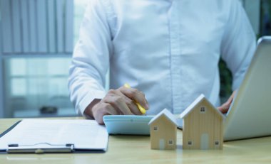 Ev kredisi harcamalarını özetlemek ve gözden geçirmek için iş adamının el çabukluğu hesap makinesine yakın plan. Mortgage yeniden finanse etme, finansal planlama ve kişisel bütçe yaşam tarzı kavramı.