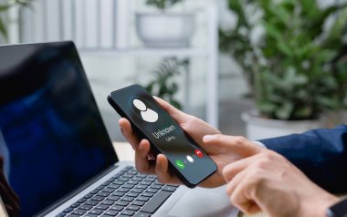 İş adamı akıllı telefondan dolandırıcılık ya da spam uyarısı alıyor. Kırmızı uyarı sembolleri, dijital mahremiyet ve çevrimiçi güvenliğin önemini vurgulayan spam aramaları ve siber dolandırıcılığı gösteriyor.