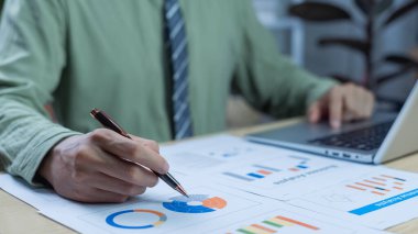 Finansal işadamı, pazar araştırma raporları ve gelir istatistiklerini kullanarak şirketin performans grafiklerini kâr ve büyüme için analiz ediyor. Finansal ve muhasebe sektörü kavramı.